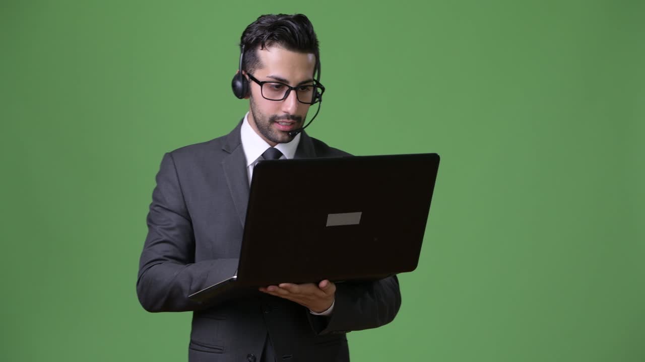 joven empresario persa barbudo y guapo contra un fondo verde