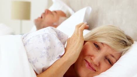 woman covering her ears as partner is snoring loudly