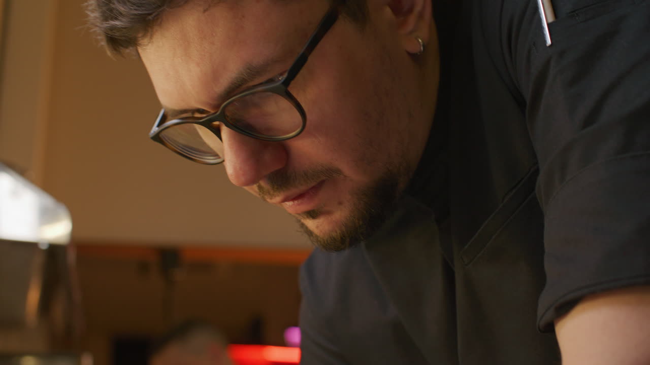 Chef profesional apuntando notas de pedidos en la cocina de un restaurante.