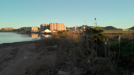 Aerial-shot-of-Spanish-apartment-blocks-near-lake-at-sunset