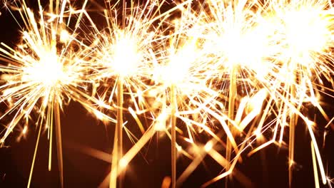 five sparklers burning on a black background