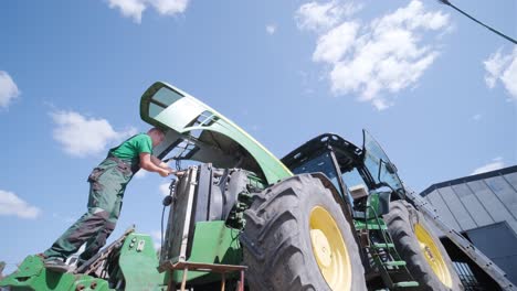 farmer mechanic repairing tractor. open tractor hood, engine. repair agricultural technology