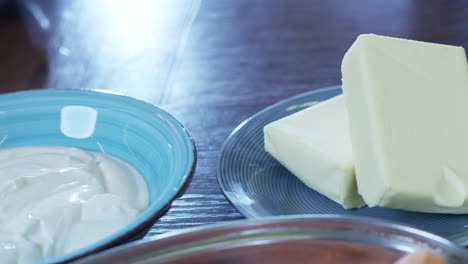 close up of fresh healthy creamy yogurt sauce in a bowl and cow butter cubes ready for tasty healthy breakfast