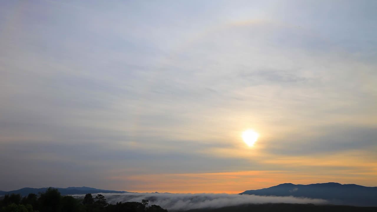 Sun halo ring over the mountain with flowing fog in the morning warm light, 4k time lapse