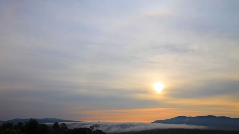 sun halo ring over the mountain with flowing fog in the morning warm light, 4k time lapse