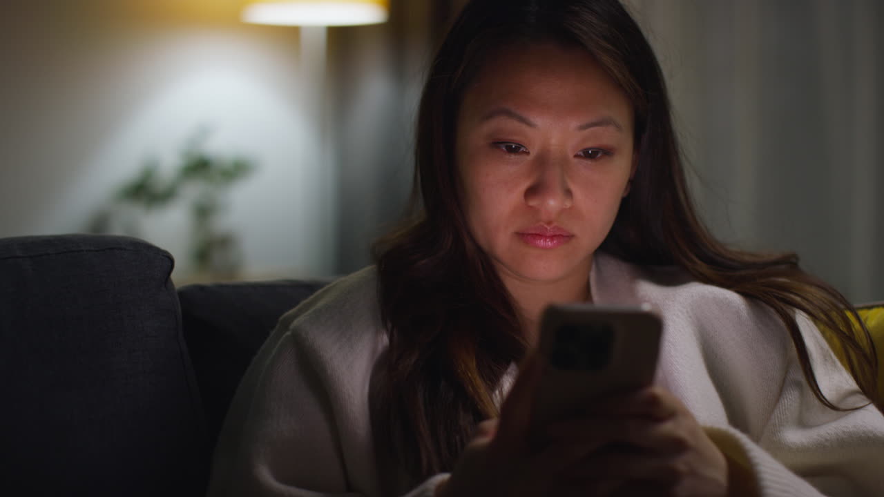 집에서 저녁을 보내고 소파에 앉아 휴대전화를 들고 인터넷이나 소셜 미디어를 스크롤하는 여성의 클로즈업 6