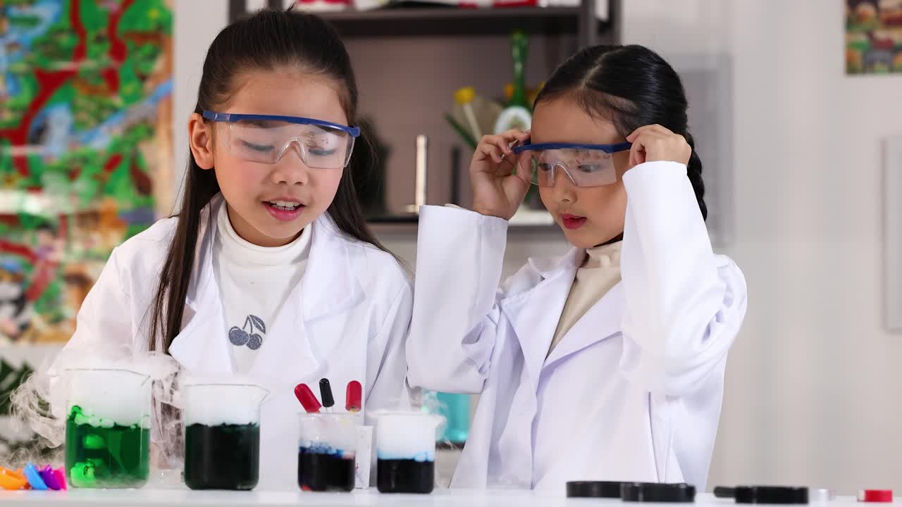 Kaksi nuorta tyttöä laboratoriotakeissa käyttää pipettejä kemian kokeisiin valoisassa laboratoriossa