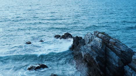 Lebendige-Bilder-Von-Wellen,-Die-Gegen-Eine-Schroffe-Klippe-Schlagen,-Und-Plätscherndem-Blauen-Wasser,-Das-Im-Kontrast-Zu-Den-Schroffen-Felsen-Steht-Und-Die-Ungezähmte-Schönheit-Der-Mexikanischen-Küste-Zeigt