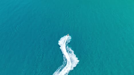 Speedboat-carving-white-wake-in-the-blue-waters-near-Corfu-Island,-Greece,-aerial-view