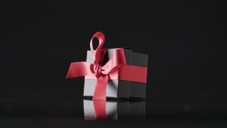 Video-of-gift-box-with-red-ribbon-and-copy-space-over-black-background