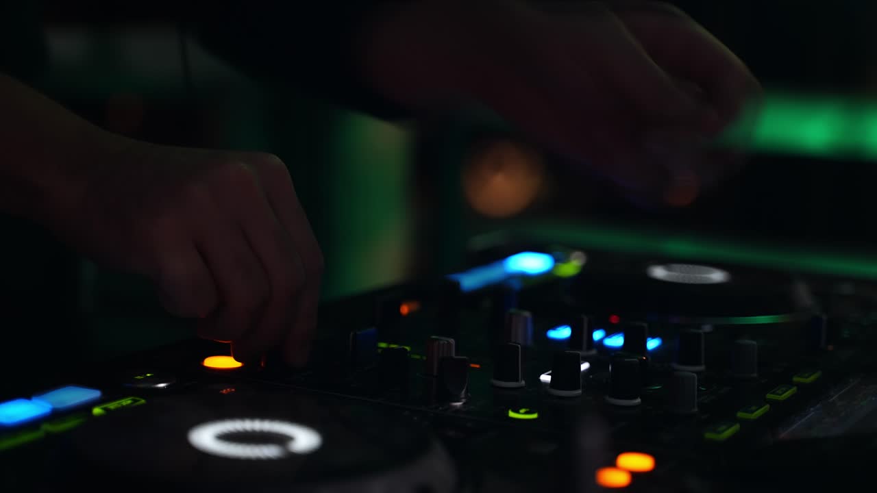 primer plano de las manos de un dj girando los botones de su mesa de mezclas digital por la noche