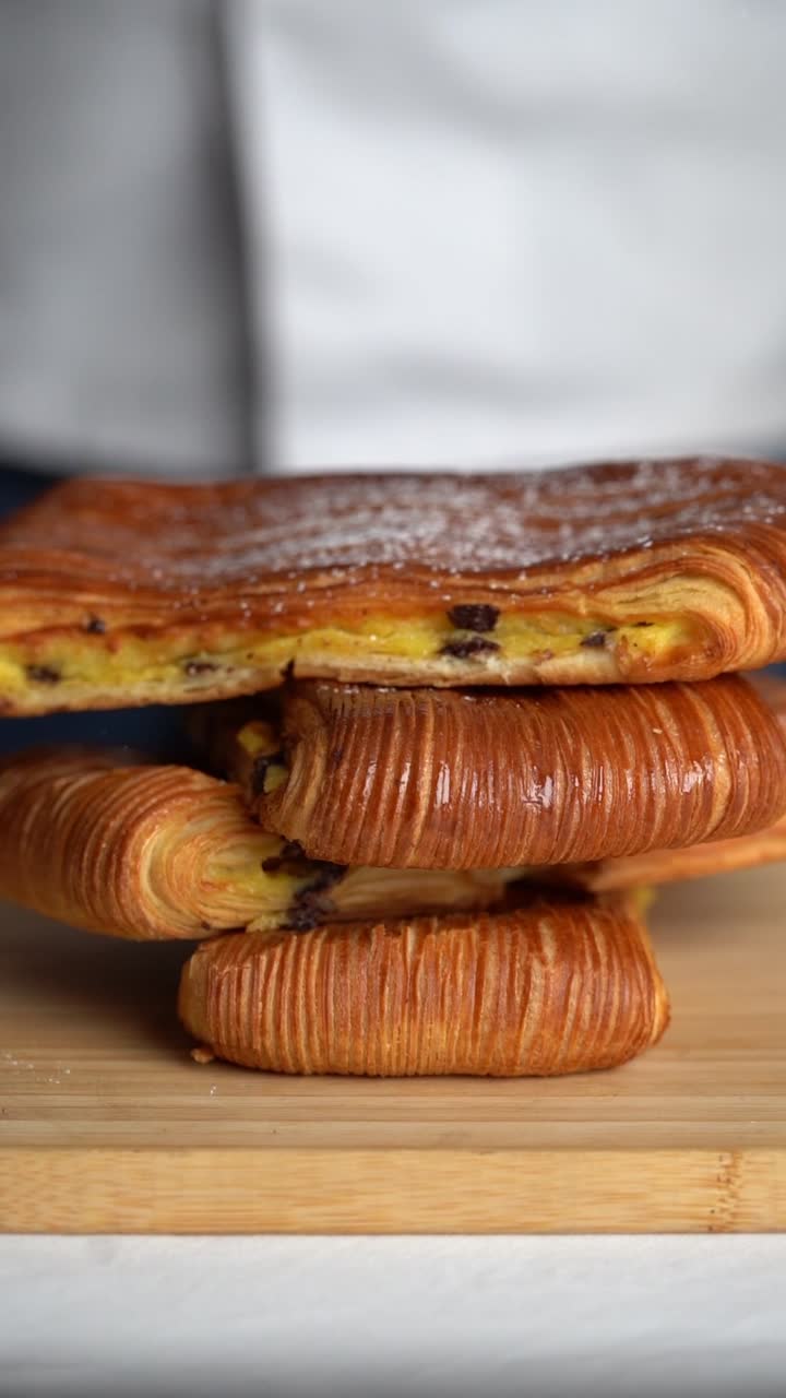 Uno chef aggiunge sale a un croissant ripieno di crema e cioccolato, primo piano, inquadratura d'inserto.