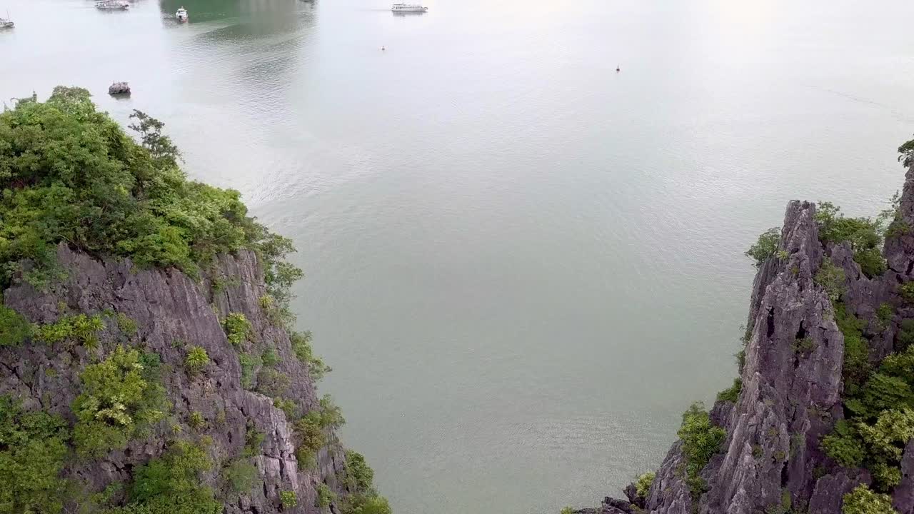 Drone flight between two rocks, you can see ships in the distance