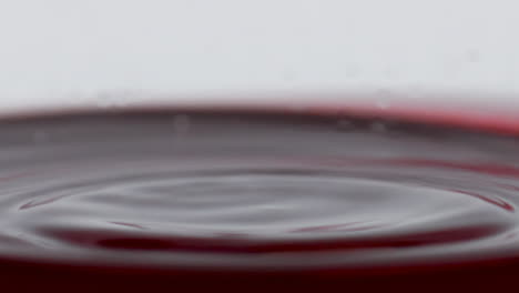 blob splashing inside wine glass closeup. drop falling slow inebriant beverage