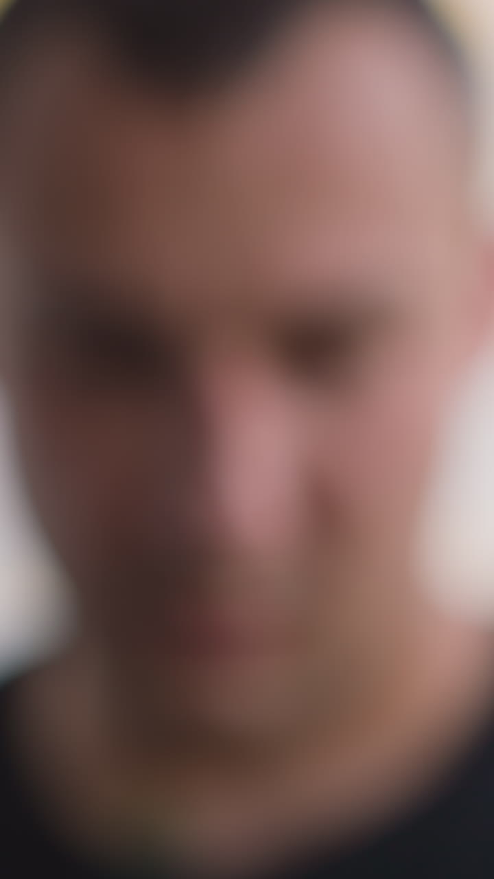 Confused man takes mobile phone from windowsill and looks at screen with message sitting in light spacious office extreme close view slow motion