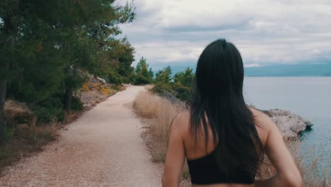 back and side of a girl jogging next to the sea