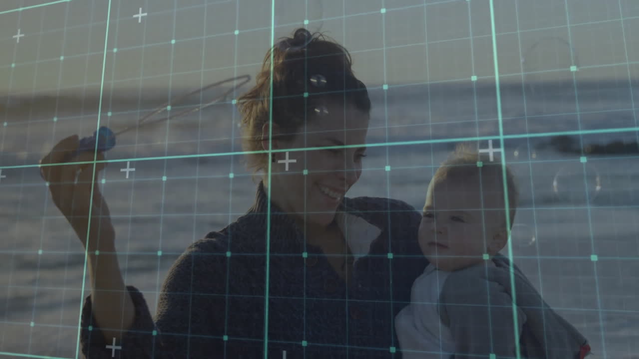 Mother holding baby at beach with digital grid overlay animation
