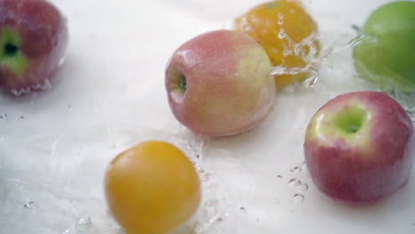 slomo de manzanas y naranjas en agua sobre fondo blanco