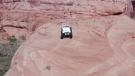 jeep todoterreno con tracción en las cuatro ruedas en lo alto de un acantilado de roca roja en el desierto de moab, utah - antena