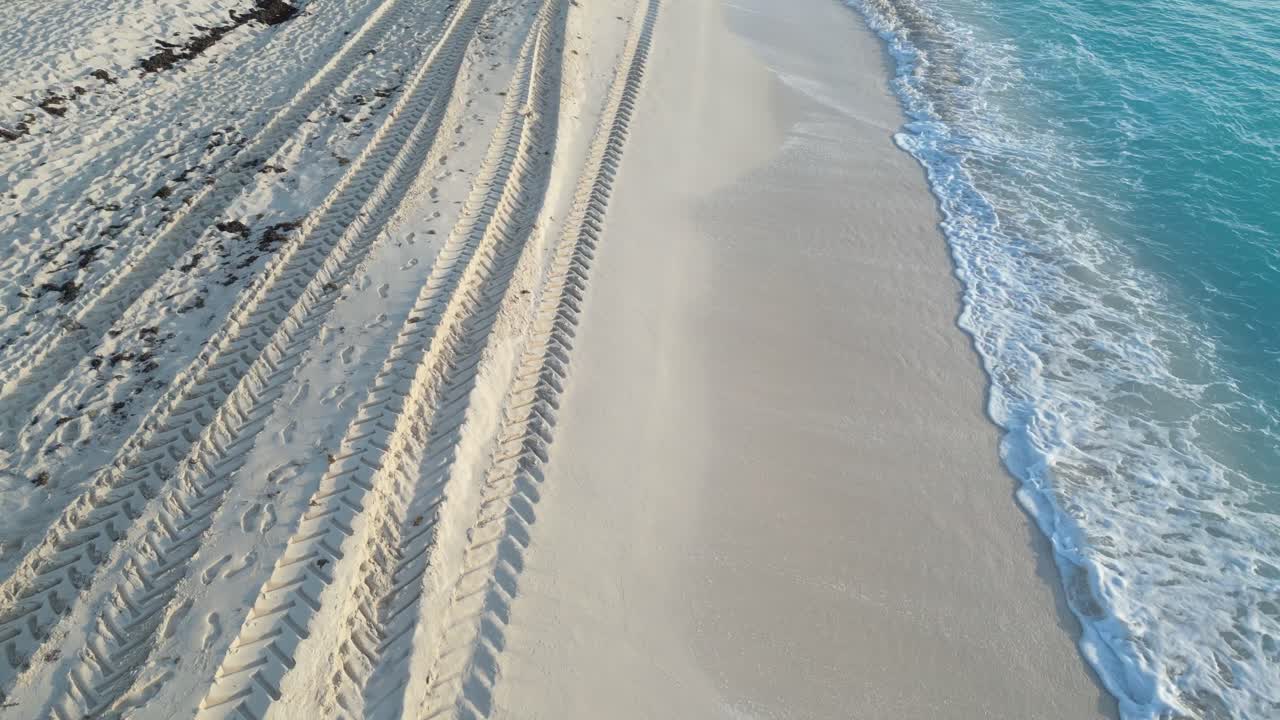 Footprints and tire tracks along the beach at Cancun with the ocean in view, playa delfines