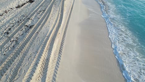 footprints and tire tracks along the beach at cancun with the ocean in view, playa delfines