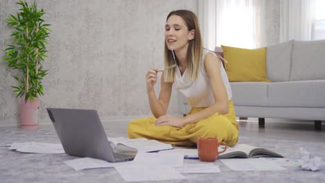 mujer joven con computadora portátil y papeles trabajando en la oficina de casa.