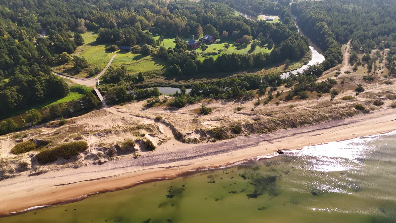Drone aerial view of river, forest, sand dunes, and coastline at Uzavas Ieteka in Latvia.