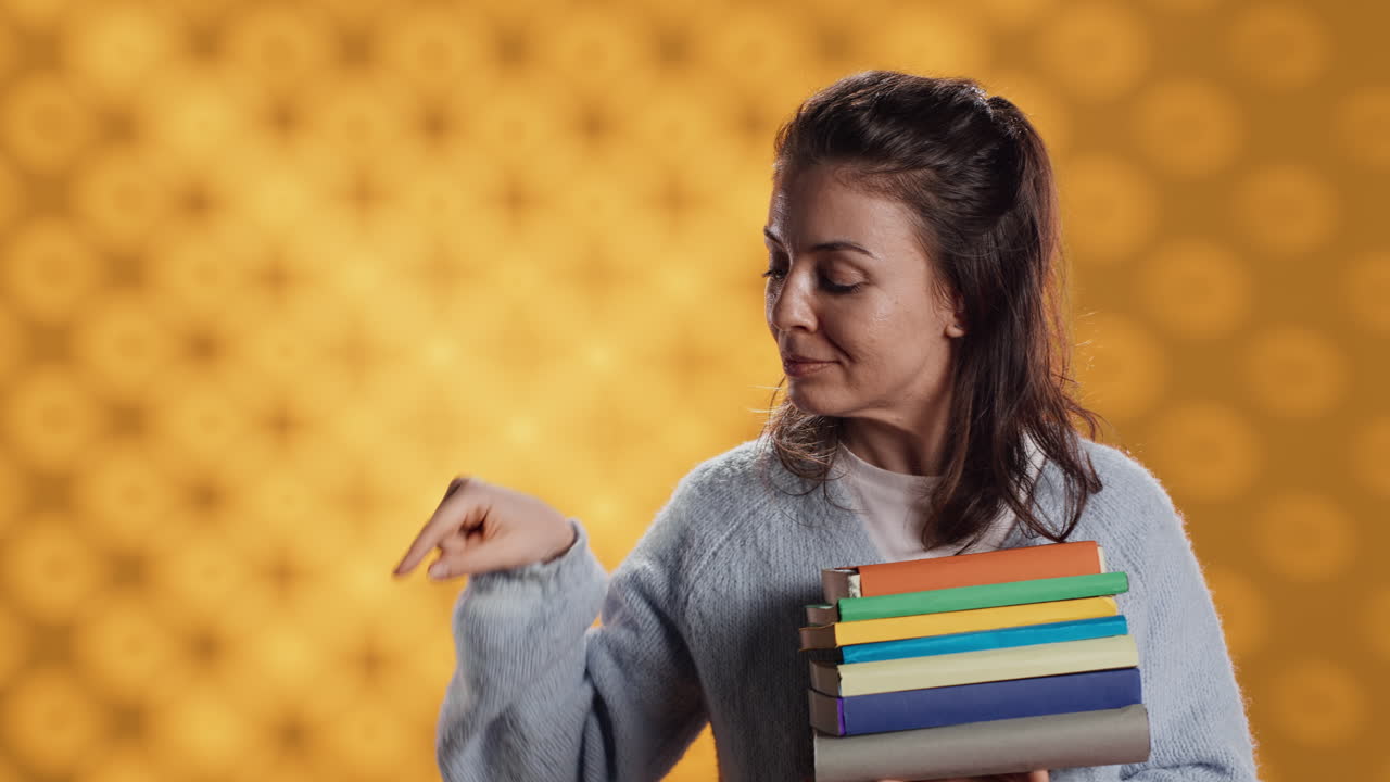 retrato de una mujer sonriente sosteniendo una pila de libros apuntando a espacios de copia vacíos