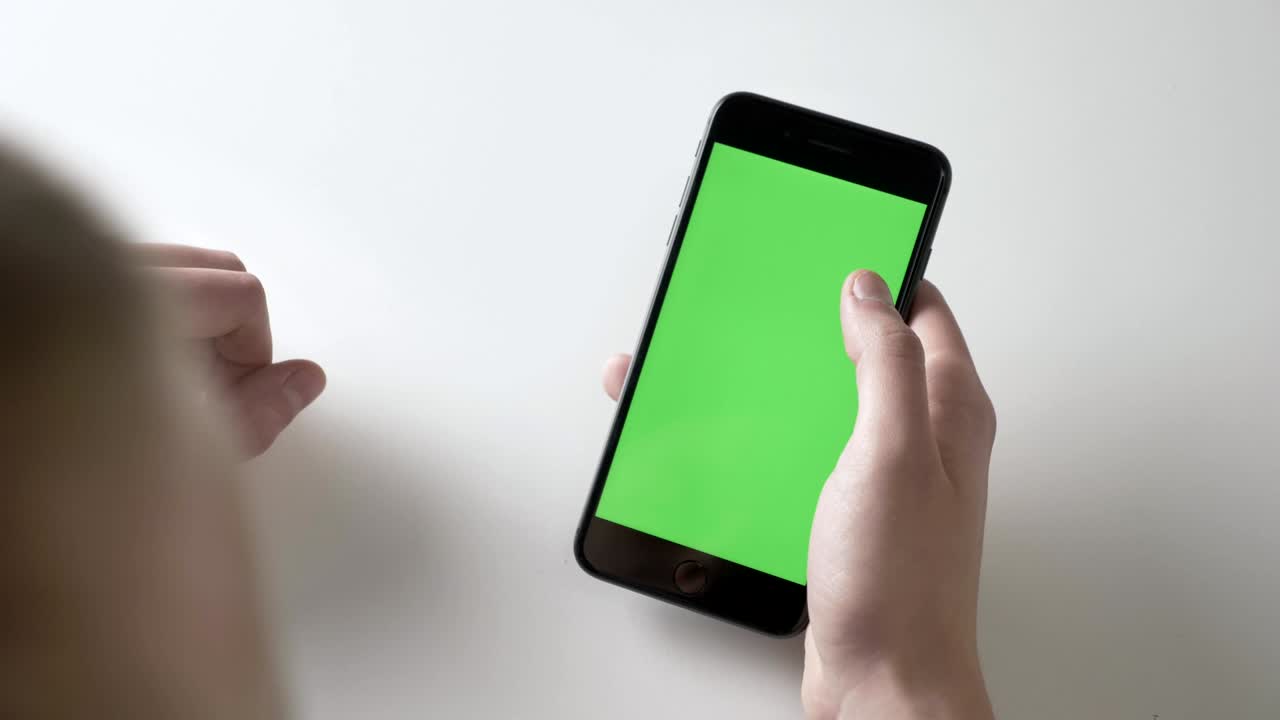 Men's hands hold a big black smartphone making pinch to zoom gesture. Green screen, chromakey concept 60 fps