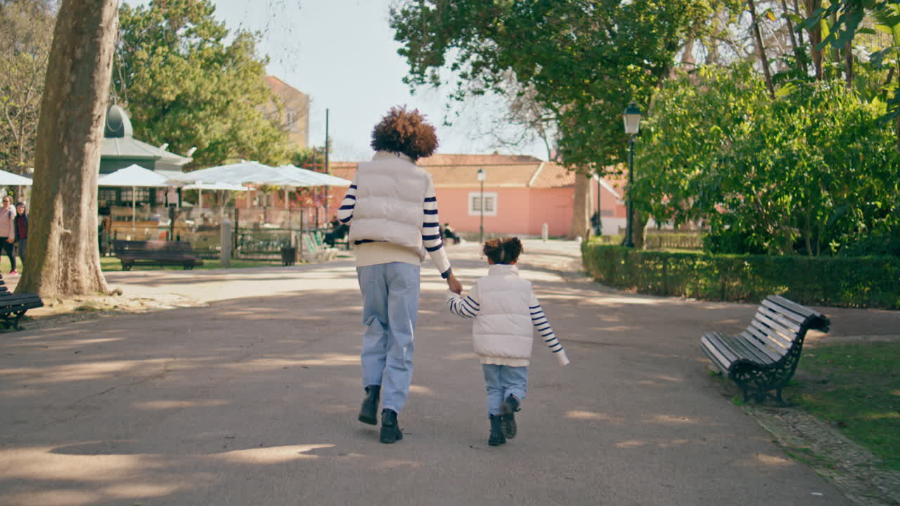 딸이 공원 도로를 따라 달리는 빛의 날. 뒷모습 행복한 가족