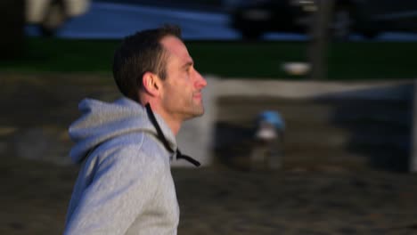 slow motion tracking shot of young caucasian man running on the beach in auckland, new zealand