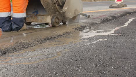 worker is using power tool to cut asphalt to correct measure