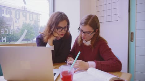 dos mujeres jóvenes estudiando en un café