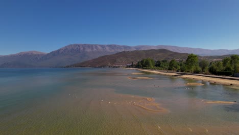 panoramic road alongside lake ohrid on shore with shallow water and birds swimming