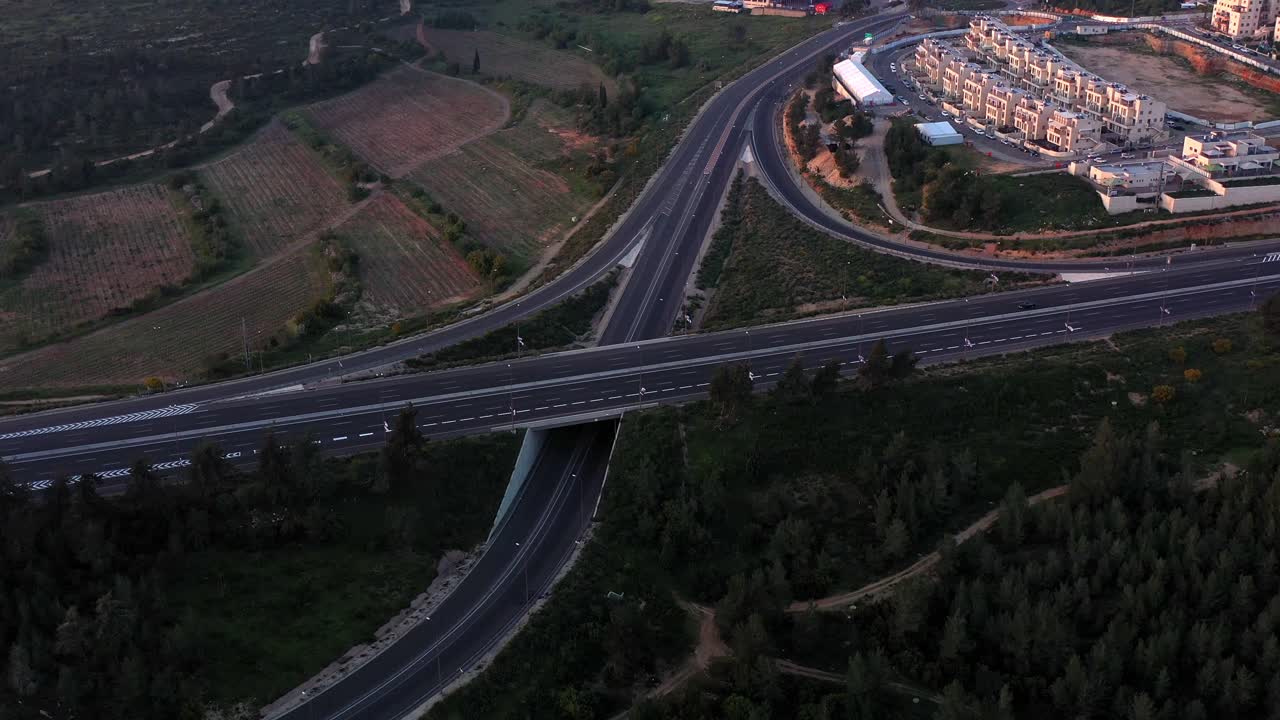 Aerial View of a Highway Interchange Amidst Forests and Fields at Dawn or Dusk