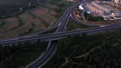 aerial view of a highway interchange amidst forests and fields at dawn or dusk