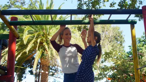 Madre-Ayudando-A-Su-Hija-A-Escalar-Barras-De-Mono-En-El-Patio-De-Recreo-4k