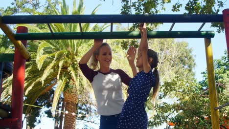 madre ayudando a su hija a escalar barras de monos en el patio de recreo 4k
