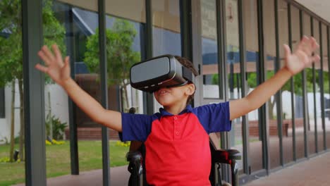 vista frontal de un escolar afroamericano discapacitado que usa auriculares de realidad virtual en el pasillo 4 de la escuela