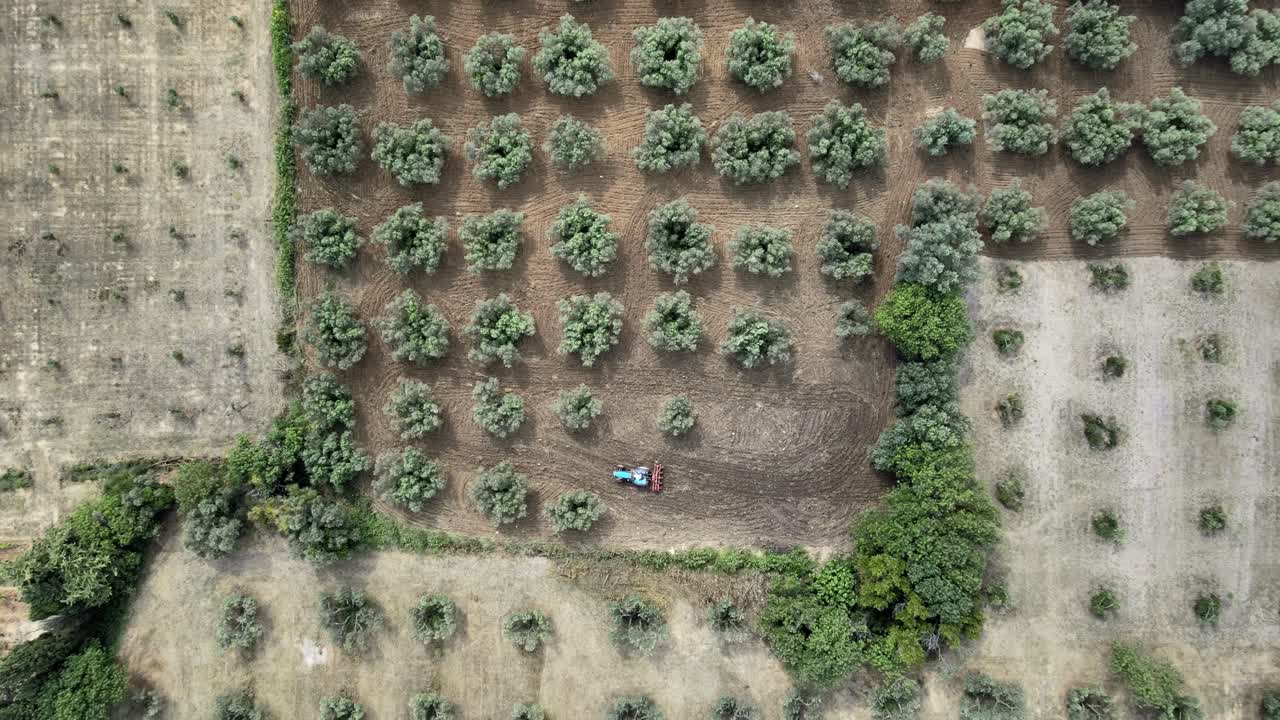 Rising bird's-eye view of a tractor harvesting crops in a patchwork of fields in Les Beaux de Provence