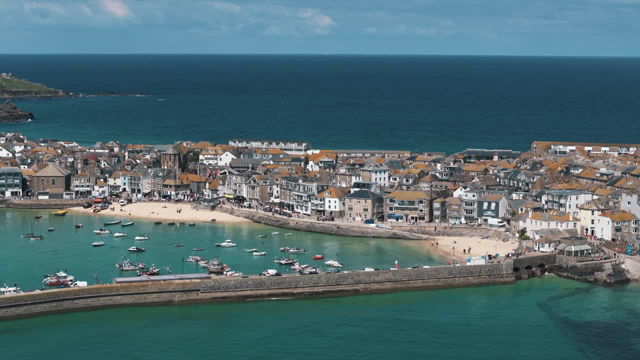 Drone ascends in right circle above St. Ives harbor and coastal buildings, establishing aerial panoramic