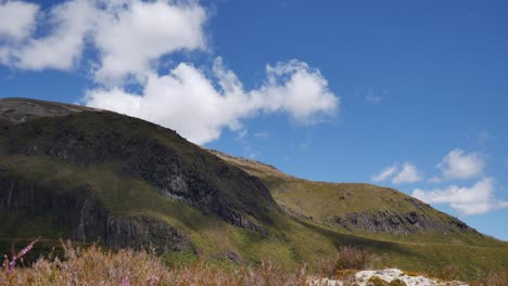 lapso de tiempo: las nubes soplan sobre la hierba verde de matas en la colina de roca volcánica