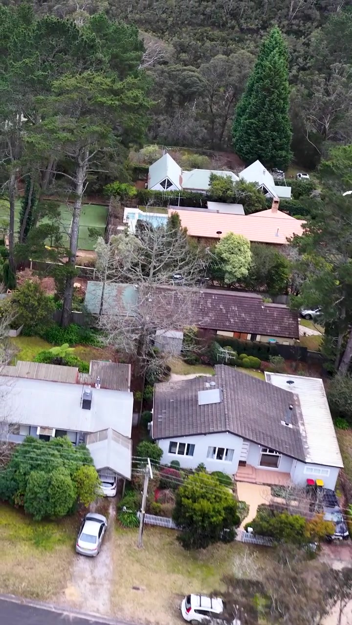 Voo de drone sobre casas residenciais e árvores de eucalipto em Wentworth Falls, Blue Mountains, Austrália