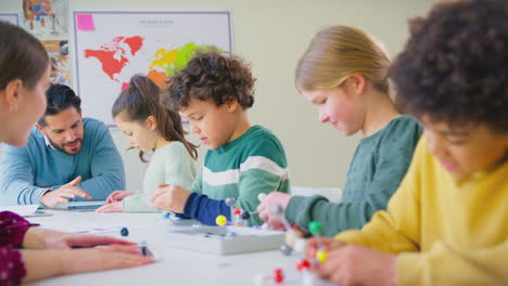 multi-cultural students with teachers in classroom studying molecular model in science class