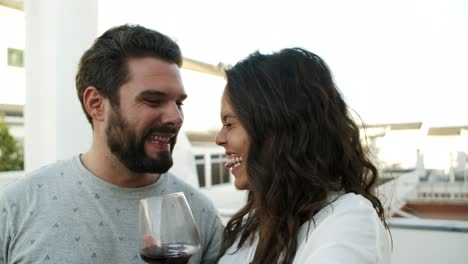 Feliz-Pareja-Joven-Brindando-Ante-La-Cámara-Y-Bebiendo-Vino-Tinto