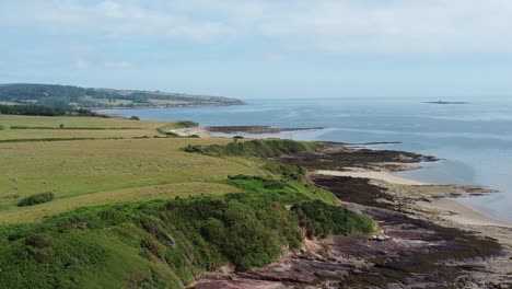 peaceful-Traeth-Lligwy-Anglesey-island-coastline-aerial-view-over-scenic-green-Welsh-coastal-hillside-cliff