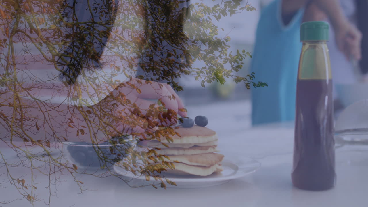 Autumn tree branches overlaying pancakes with blueberries and syrup bottle on table