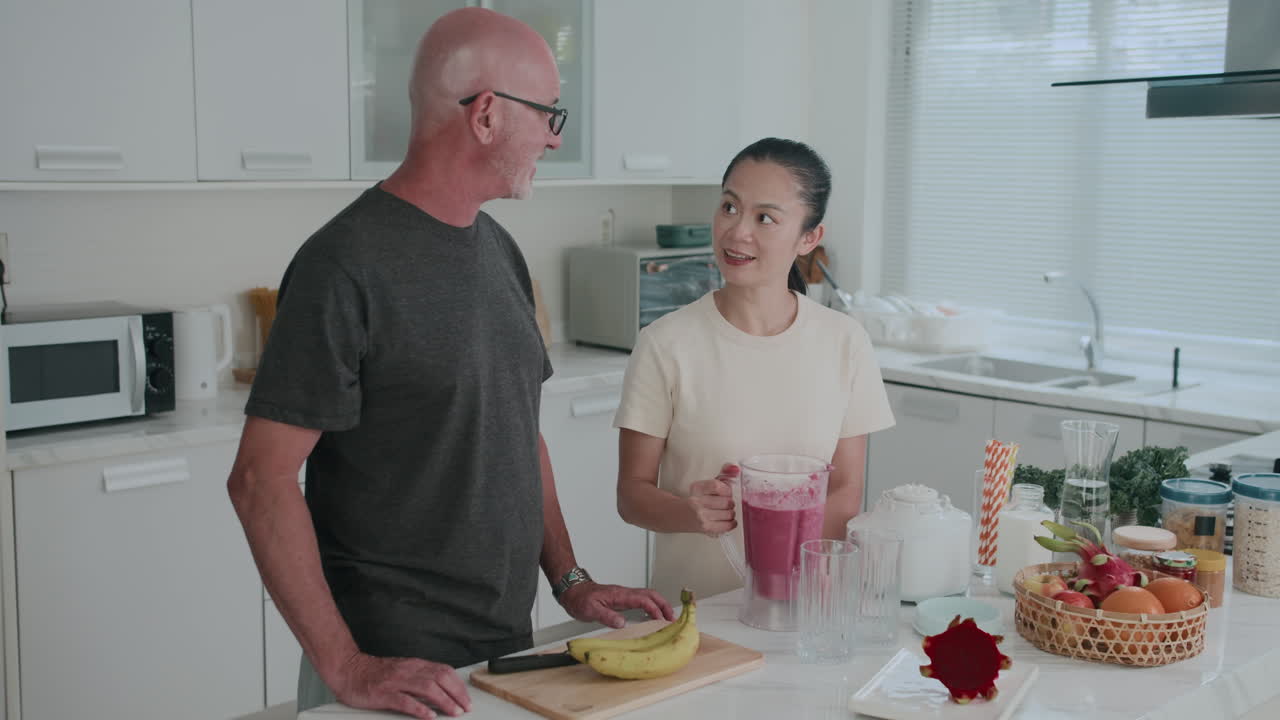Biracial Couple Pouring Smoothie into Cups during Breakfast at Home