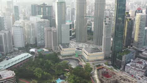 tiro inclinado desde el parque klcc de vegetación urbana, revela las icónicas torres gemelas petronas y el paisaje urbano circundante en el centro de kuala lumpur, malasia