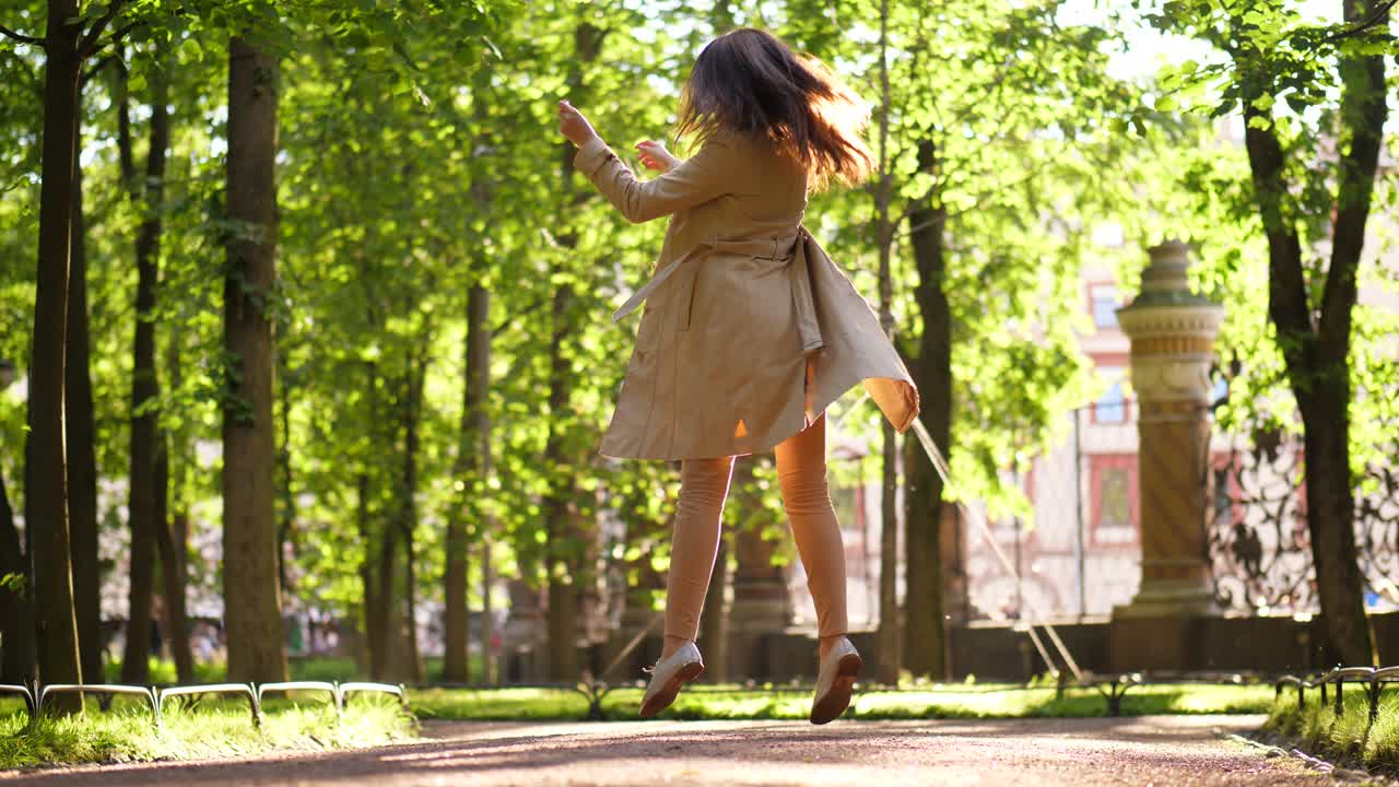 feliz mujer de negocios en abrigo de trincheira bailar y saltar en la calle